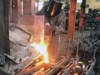um homem usando equipamentos de proteção e manuseando uma forja