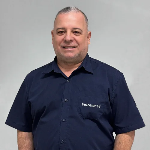 Laercio vendedor caminhao de braços cruzado, sorriso e sua camisa é da cor azul marinho.