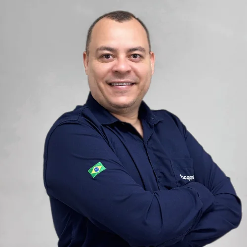 Luciano vendedor agrícola de braços cruzado, sorriso e sua camisa é da cor azul marinho.