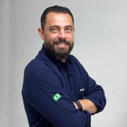 Rodrigo vendedor agrícola de braços cruzado, sorriso e sua camisa é da cor azul marinho.